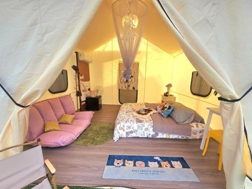 a tent with a bed and a couch in a room at Cat A Camp - Khao Yai 