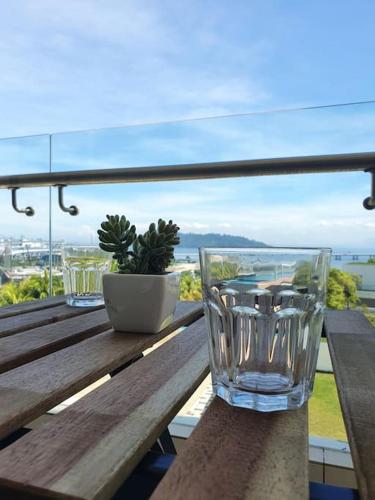 two empty glasses sitting on a wooden table on a balcony at Southbay Seaview Condo A11 #Queensbay #SPICE in Bayan Lepas
