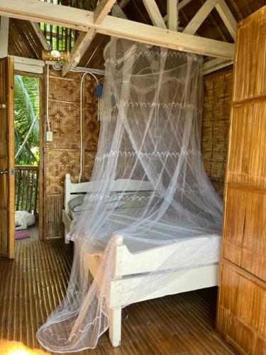 a bedroom with a bed with a mosquito net at Boochee Beach in Tampi