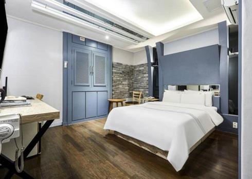 1 dormitorio con 1 cama blanca grande y escritorio en 24 Block Hotel, en Suwon