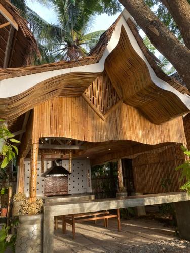 a wooden building with a bench under a tree at Boochee Beach in Tampi