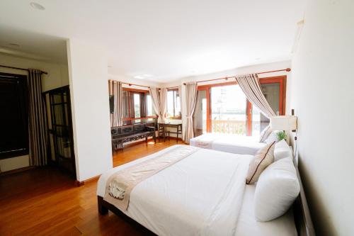 a bedroom with a large white bed and a desk at B'Lan Riverside Villa in Hoi An