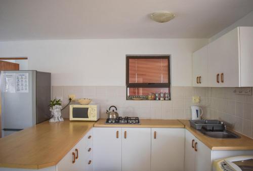 a kitchen with white cabinets and a white refrigerator at Sea Gem with a stunning view in Boggomsbaai