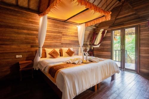 - une chambre avec un lit dans une pièce dotée de murs en bois dans l'établissement Bali Sesandan Garden, à Tabanan