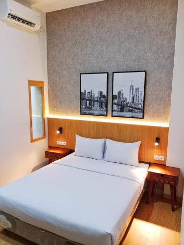 een bed in een kamer met drie foto's aan de muur bij Hotel Andita Syariah in Surabaya
