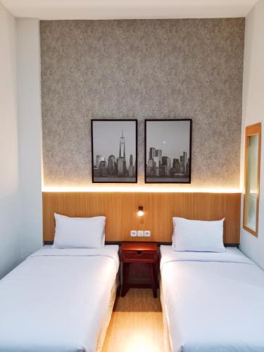 two beds in a room with three pictures on the wall at Hotel Andita Syariah in Surabaya