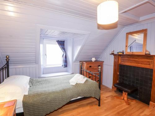 um quarto com uma cama e uma lareira em Jubilee Cottage em Uig
