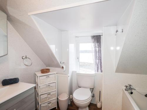a white bathroom with a toilet and a sink at Jubilee Cottage in Uig