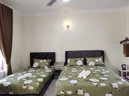 a bedroom with two beds with flowers on the sheets at Heal Inn Roomstay - Islam Guest in Kangar
