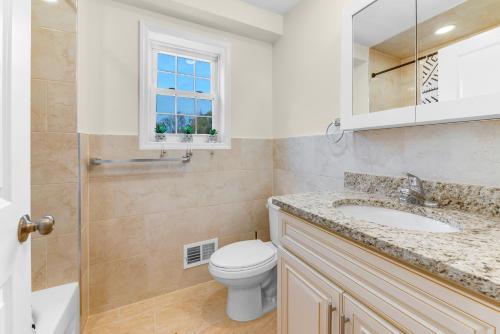 a bathroom with a toilet and a sink and a window at Cozy 3BR Newark Apt with Easy Access to NYC and Seton Hall in Newark