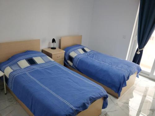 - 2 lits avec des draps bleus dans une chambre dans l'établissement Sunny Morn Qawra, St Paul's Bay Malta, à San Pawl il-Baħar
