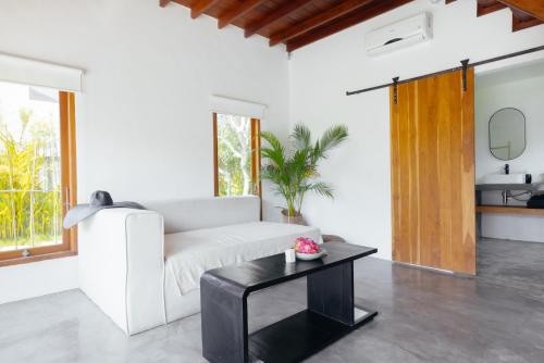 sala de estar con sofá blanco y mesa negra en HOLA villas & lofts Uluwatu, en Uluwatu