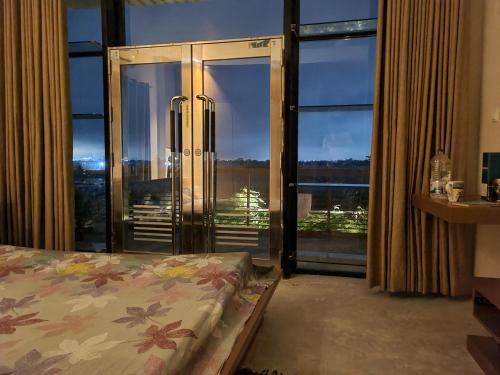 a bedroom with a bed and a large glass door at Jolshiri Vacation House in Dhaka