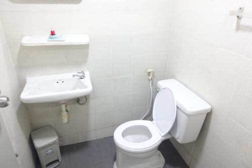 La salle de bains blanche est pourvue de toilettes et d'un lavabo. dans l'établissement ขนิษฐา อพาร์เม้น, à Thung Si Kan