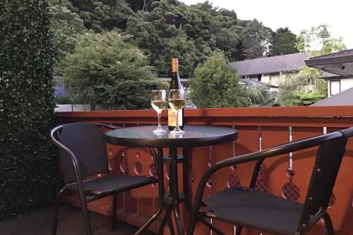uma mesa com dois copos de vinho numa varanda em The Swiss Chalet Holiday Apartment 4, Bay of Islands em Paihia