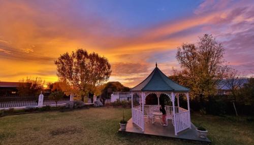 a girl in a gazebo in a yard with a sunset at Colesview Guest House in Colesberg