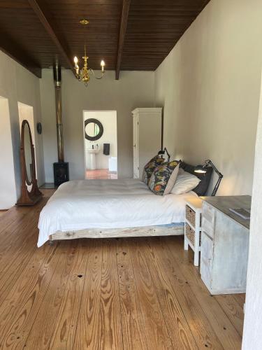 1 dormitorio con 1 cama grande y suelo de madera en Willdenowia Guestsuite at Waboom Family Farm, en Stanford
