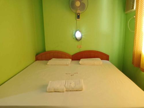 a green room with a bed with two towels on it at WJV INN JY in Cebu City