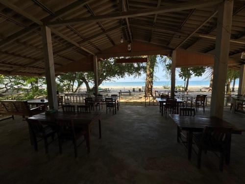 an empty restaurant with tables and chairs and the beach at Changthong Bungalow in Koh Chang Ranong