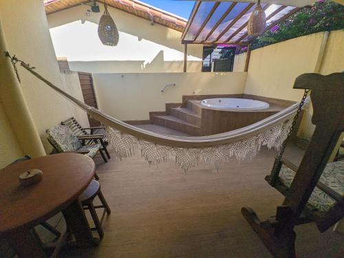 a hammock in the middle of a room with a tub at Pousada Lua Nova Pipa Chales com Hidromassagem e Jacuzzi in Pipa