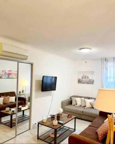 un salon avec un canapé et une télévision sur un mur dans l'établissement Cœur de Cannes, à Cannes