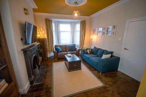 a living room with a blue couch and a tv at 4-bed botanical retreat in Plymouth