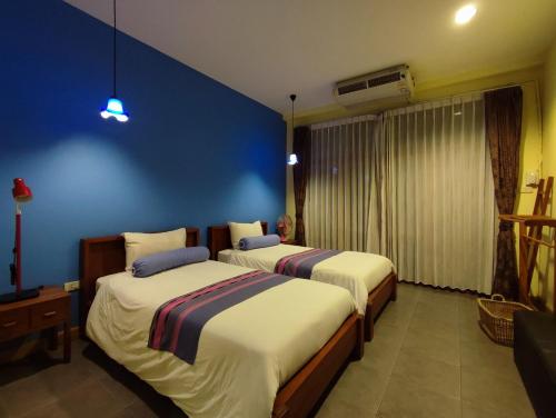 two beds in a room with a blue wall at AuangKham Resort in Lampang