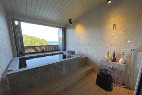 a bathroom with a large tub with a window at 鵜原館 -Ubarakan- in Katsuura
