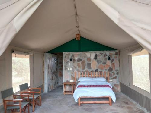 1 dormitorio en una tienda de campaña con 1 cama y sillas en Resian Mara Camp, en Talek
