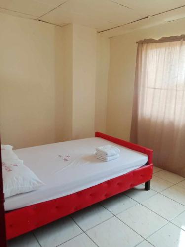 a red bed in a room with a window at WJV INN JY in Cebu City