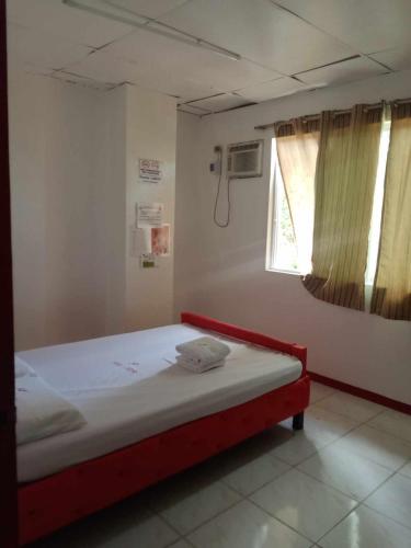 um quarto com uma cama com uma moldura vermelha e uma janela em WJV INN JY em Cebu