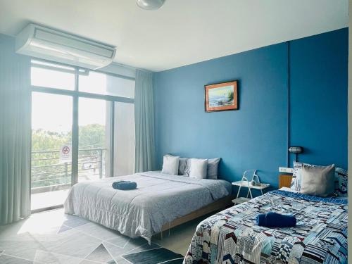 ein blaues Schlafzimmer mit 2 Betten und einem Fenster in der Unterkunft HOMEY-Don Mueang Airport Hostel in Bangkok