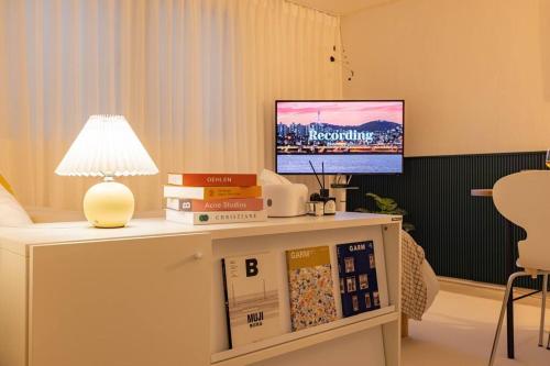 a room with a table with books and a tv at Warm Place in Seoul