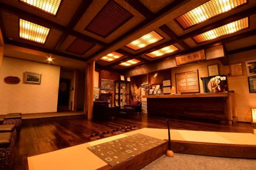 a living room with a fireplace and wooden ceilings at 鵜原館 -Ubarakan- in Katsuura