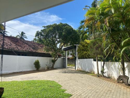 a house with a white fence and a driveway at New White House in Aluthgama