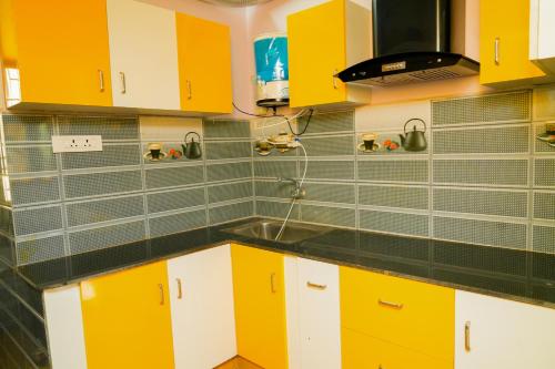a kitchen with yellow and white cabinets and a sink at Prabas - Farm house in Puducherry