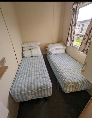 two beds in a small room with a window at A&J Caravan 14 in Kinmel Bay