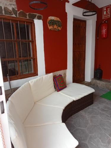 a white couch in a room with a red wall at El Canchal de Eladia in Valdeverdeja
