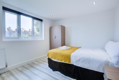 a bedroom with a large bed and two windows at Charming 7 bedroom house sleeps up to 13 guests in Romford