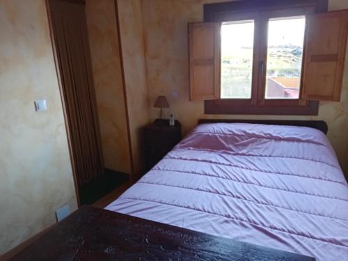 a bed in a small room with a window at El Canchal de Eladia in Valdeverdeja