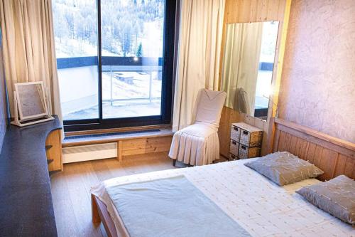 1 dormitorio con 1 cama, 1 silla y 1 ventana en Le plus grand appartement, 150 M2, et la plus belle vue d'Isola 2000 Front de Neige en Isola 2000