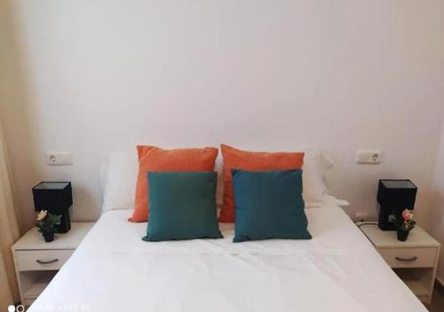 Una cama blanca con almohadas de color naranja y azul. en FH CAMP PRECIÓS II, en Altea
