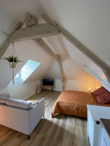 ブリーヴ・ラ・ガイヤルドにあるAppartement chaleureux - Clim réversible - Meublé A-Zのベッドルーム1室(ベッド1台、屋根裏部屋のソファ付)