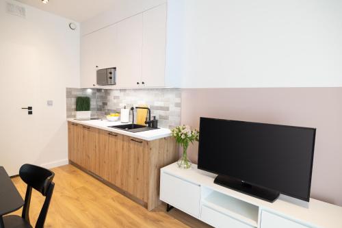 a living room with a tv and a kitchen with a counter at B85 Suites in Warsaw