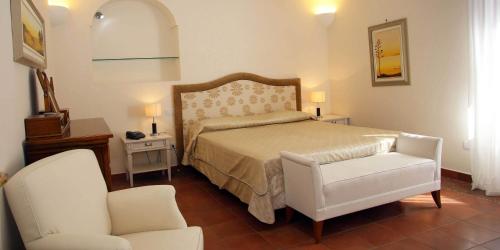 a bedroom with a bed and a white chair and a chair at Palazzo Iaquinto in Santa Maria di Castellabate