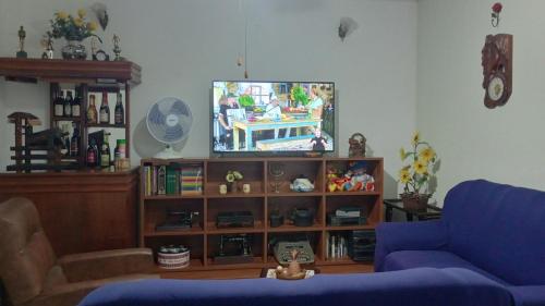 a living room with a blue couch and a television at CASA de 2 QUARTOS in Guaratinguetá