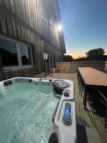 un jacuzzi installé sur une terrasse à côté d'un bâtiment dans l'établissement Gîte 14 personnes - 10 minutes de Gerardmer - Jaccuzzi, à Gerbépal