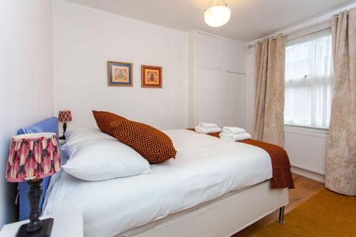 a bedroom with a bed with white sheets and a window at Italianflat - Kilburn Art Style in London