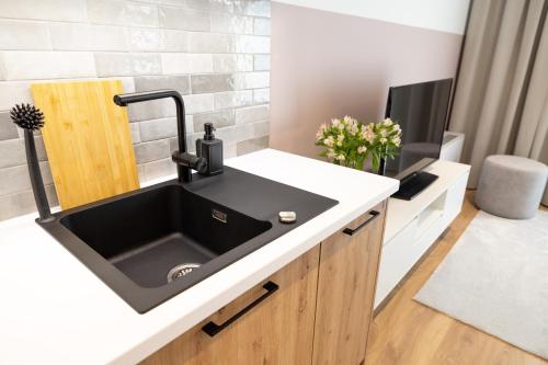 a kitchen with a black sink and a tv at B85 Suites in Warsaw