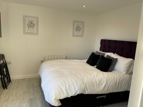 una camera da letto con un grande letto con lenzuola bianche e cuscini neri di Riverside Annex at Ashbank a Penrith